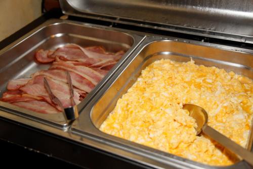 a tray of scrambled eggs and bacon in an oven at Hotel Villa Rosa in Grado