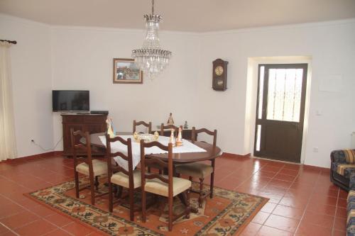 a dining room with a table and chairs and a chandelier at Vivenda Maria da Nazaré in Picamilho