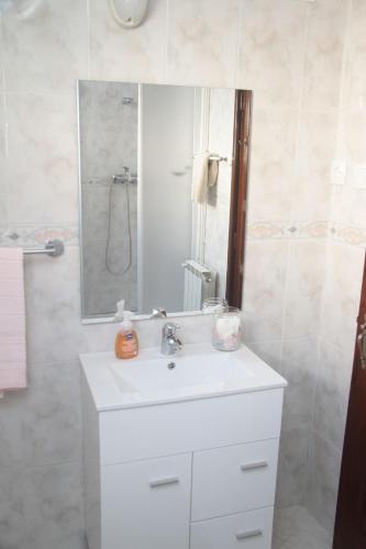 a bathroom with a white sink and a mirror at Vivenda Maria da Nazaré in Picamilho