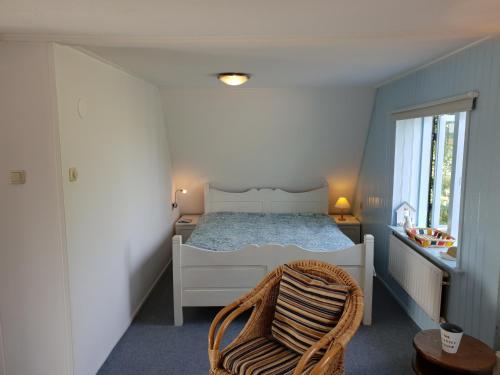 - une chambre avec un lit blanc et une chaise dans l'établissement Appartement Soigner!, à Egmond-Binnen