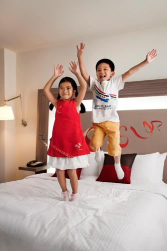 two children jumping on top of a bed at Novotel Paris Rueil Malmaison in Rueil-Malmaison