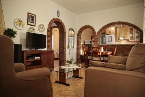 a living room with a couch and a tv and a table at Casa Rural Típica Andaluza, WiFi,Piscina, Barbacoa, Aire Acondicionado, 5min Centros in Alhaurín el Grande