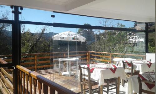 a balcony with tables and chairs and an umbrella at Pousada La Sierra in Campos do Jordão