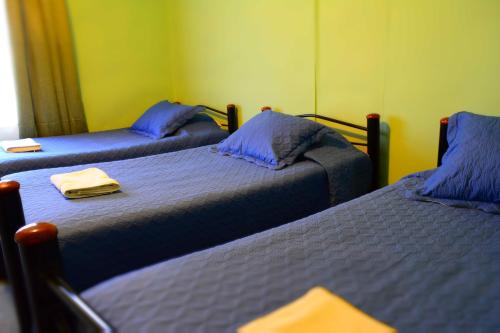 a room with two beds with blue sheets at Hostal Aventura Austral in Punta Arenas