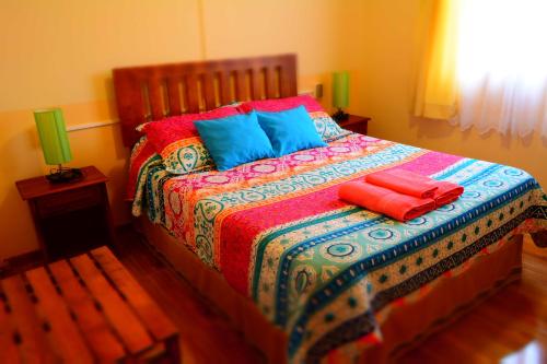 a bed with colorful blankets and pillows on it at Hostal Aventura Austral in Punta Arenas