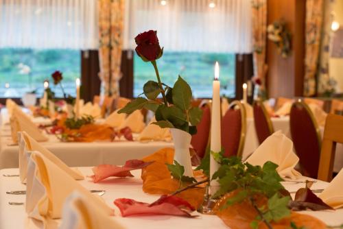 a table with a rose in a vase with candles at Hotel & Restaurant Krone in Kestert