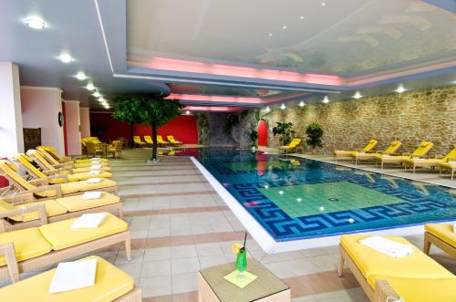a large swimming pool in a hotel with yellow chairs at Schmelmer Hof Hotel & Resort in Bad Aibling
