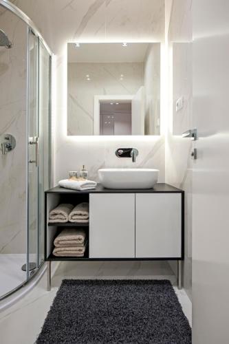 a white bathroom with a sink and a mirror at Apartments Vincero in Rovinj