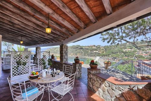 a patio with a table and chairs on a stone wall at Rosa dei Venti in Capoliveri