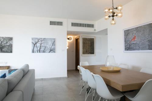 a dining room with a wooden table and white chairs at Amazing sea View, steps to beach, near Tel-aviv in Bat Yam