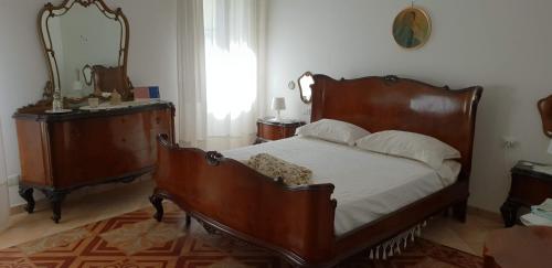 a bedroom with a large wooden bed and a mirror at B&B Il Glicine in Badia Polesine