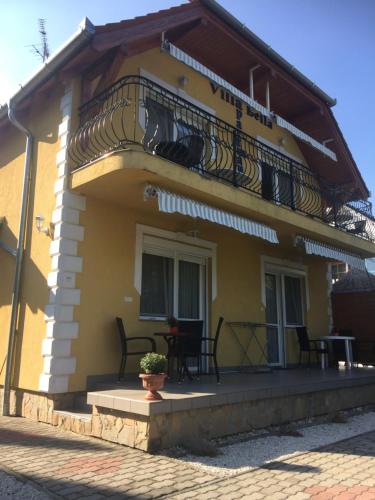 a yellow house with a balcony and a table at Villa Bella Apartman in Bük