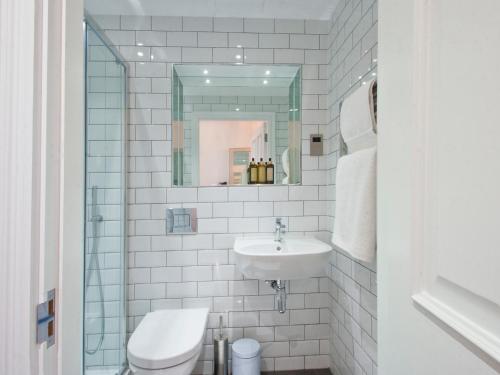 a white bathroom with a sink and a mirror at W12 Rooms in London