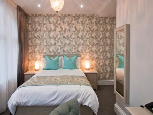 a bedroom with a bed with blue pillows and a mirror at W12 Rooms in London