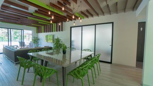 a dining room with a table and green chairs at BEE Suites Santa Ana in Santa Ana