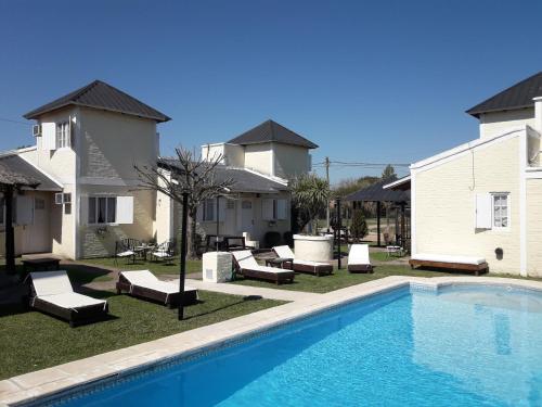 a swimming pool in front of a house with lounge chairs at Altos de Unzué in Gualeguaychú