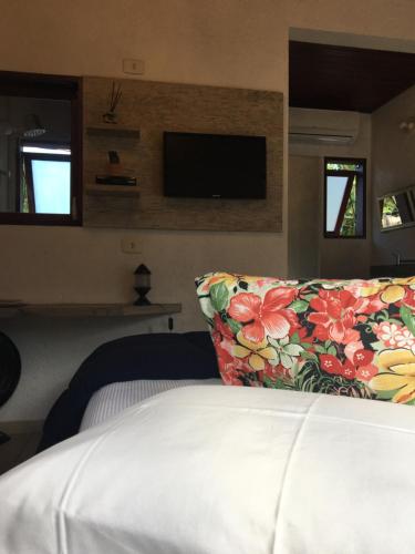 a bedroom with a bed with a pillow and a tv at Pousada Preamare in Ubatuba
