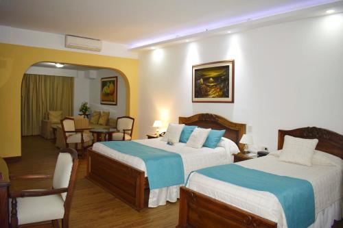 Habitación de hotel con 2 camas y sala de estar. en El Gran Hotel de Pereira, en Pereira