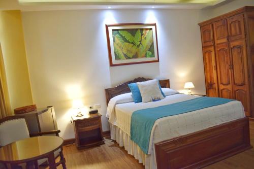 a bedroom with a large bed and a table and a table at El Gran Hotel de Pereira in Pereira