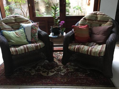 two wicker chairs with pillows in a living room at Pousada Preamare in Ubatuba