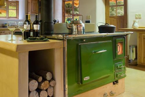 un viejo horno verde en una cocina con copas de vino en La Confluencia Lodge en El Bolsón