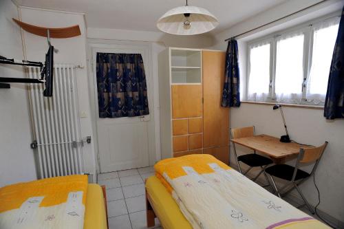 a room with two beds and a desk and a table at Niros Bed & Breakfast in Basel