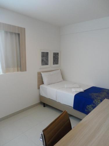 a bedroom with a bed and a table and a chair at Flat de Luxo em Boa Viagem 2 Qtos in Recife