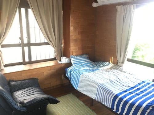 a bedroom with two beds and a chair and windows at Minnkayado intoparitosura in Miyako Island