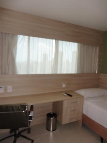 een slaapkamer met een bureau, een bed en een stoel bij Flat Boa Viagem Premium 2qtos in Recife