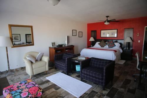 a hotel room with a bed and a couch and chairs at Trojan House in Ensenada