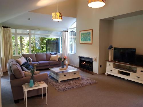 a living room with a couch and a tv at Centennial House Taupo in Taupo