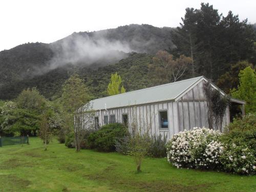 a building in a field next to a mountain at Smiths Farm Holiday Park in Linkwater