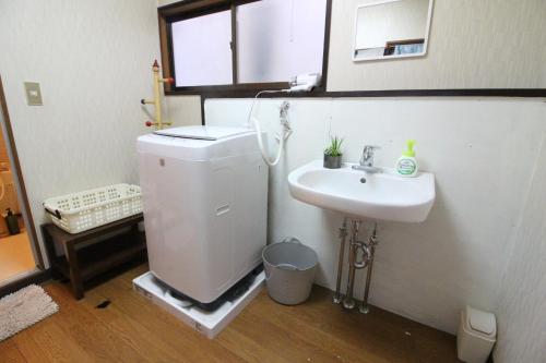 ein Badezimmer mit einem WC, einem Waschbecken und einem Spiegel in der Unterkunft Yadokari House in Okayama