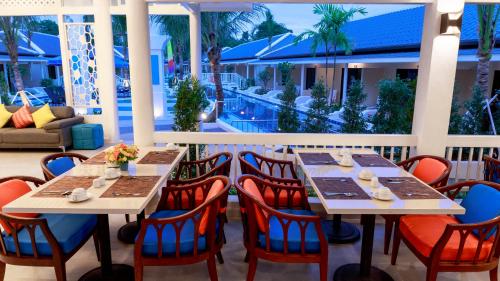 um restaurante com mesas e cadeiras e uma piscina em Tuana Hotels Brook Pool Access em Chalong