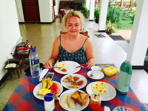 a woman sitting at a table with plates of food at Sigiri Rainbow Lodge in Sigiriya