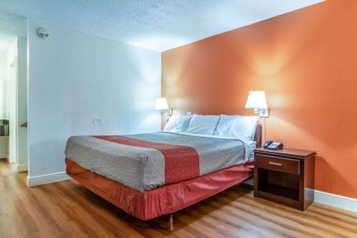 a bedroom with a bed with an orange wall at Motel 6-Natchitoches, LA in Natchitoches