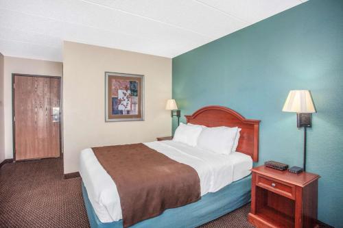 a hotel room with a bed and a table with a lamp at AmericInn by Wyndham St. Peter in Saint Peter