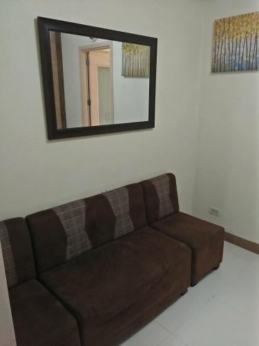 Sofá marrón en la sala de estar con espejo en CHATEAU ELYSSE a4 near SM Mall,AIRPORT Wifi, en Manila