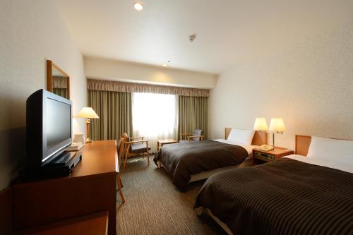 a hotel room with two beds and a flat screen tv at Hotel Concorde Hamamatsu in Hamamatsu