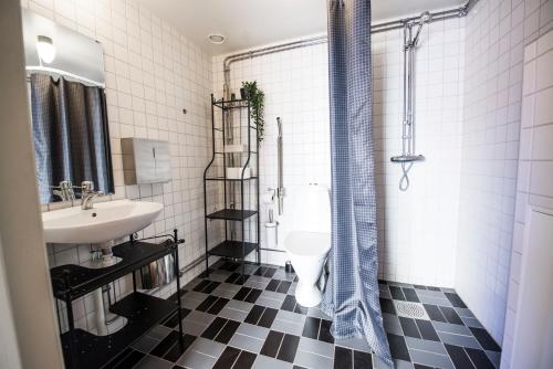 a black and white bathroom with a sink and a shower at Hotell Gamla Fängelset in Umeå