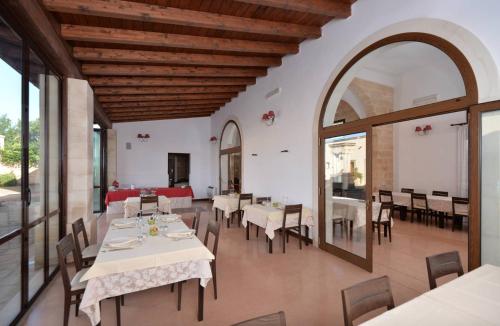 una sala da pranzo con tavoli e sedie bianchi di Masseria Li Campi a Cavallino di Lecce