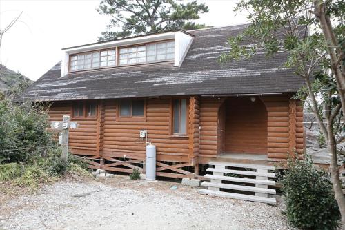 a wooden cabin with a gambrel roof at Okinoshima Resort Island Park Hotel in Tsudo