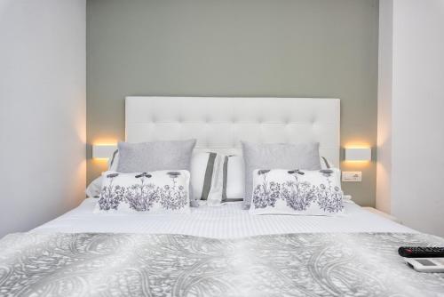 Un dormitorio con una gran cama blanca con dos almohadas. en Seafront La Malagueta II, en Málaga