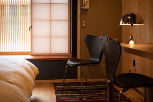 a bedroom with two chairs and a desk and a bed at Hotel Koo Otsuhyakucho in Otsu