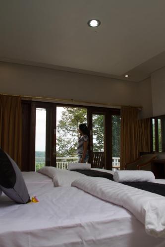 a woman standing in a room with four beds at Mandhasativa Homestay in Singaraja
