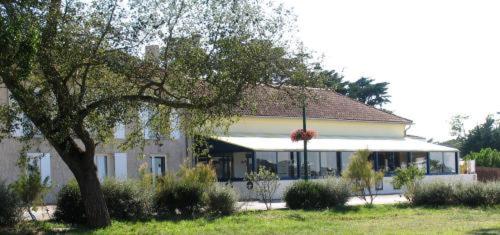 een groot wit gebouw met een boom ervoor bij Hôtel - Restaurant La Chaloupe in Le Port-des-Barques