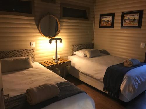 um quarto com 2 camas, um espelho e um candeeiro. em Timmerstuga em Malelane