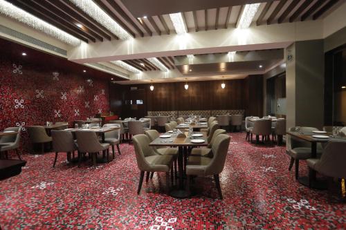 a restaurant with tables and chairs on a red carpet at Hotel Radiance in Ahmadnagar