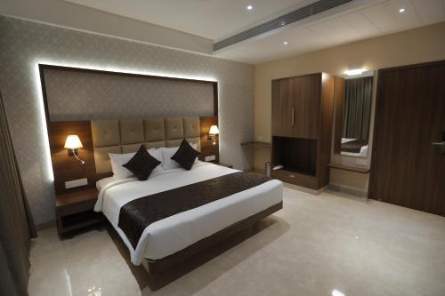 a bedroom with a large bed and a flat screen tv at Hotel Radiance in Ahmadnagar
