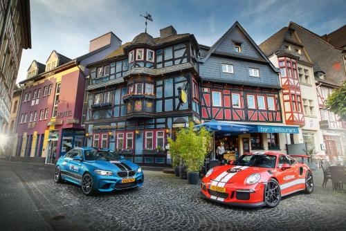 dwa samochody zaparkowane przed budynkiem w obiekcie Hotel Blaue Ecke w mieście Adenau